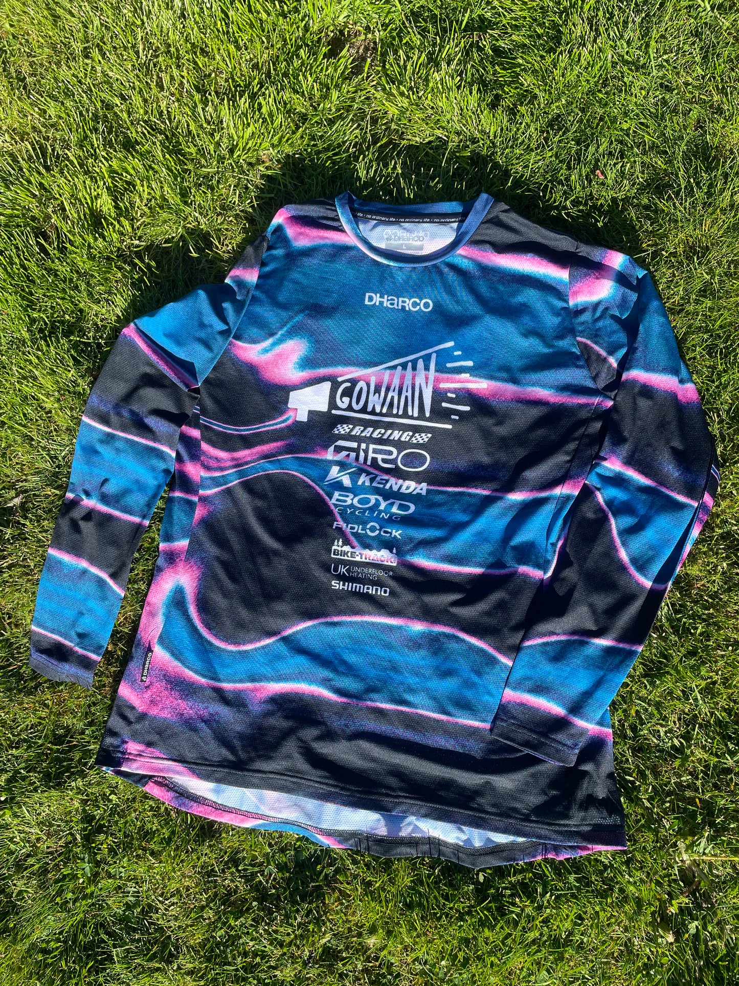 Blue and black Gowaan Racing long-sleeve Dharco jersey with brand logos on grass