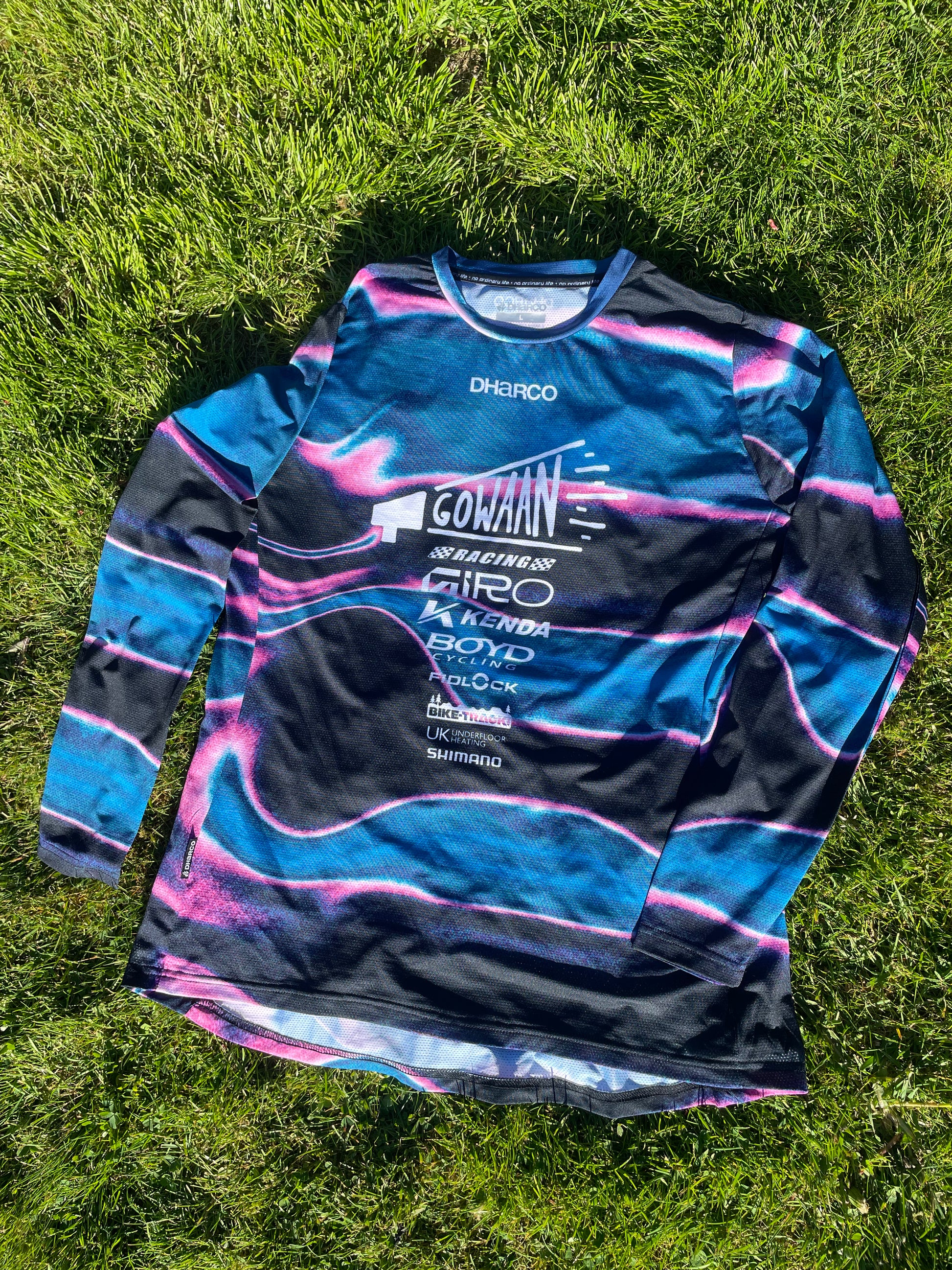 Blue and black Gowaan Racing long-sleeve Dharco jersey with brand logos on grass