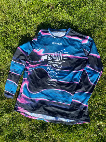 Blue and black Gowaan Racing long-sleeve Dharco jersey with brand logos on grass