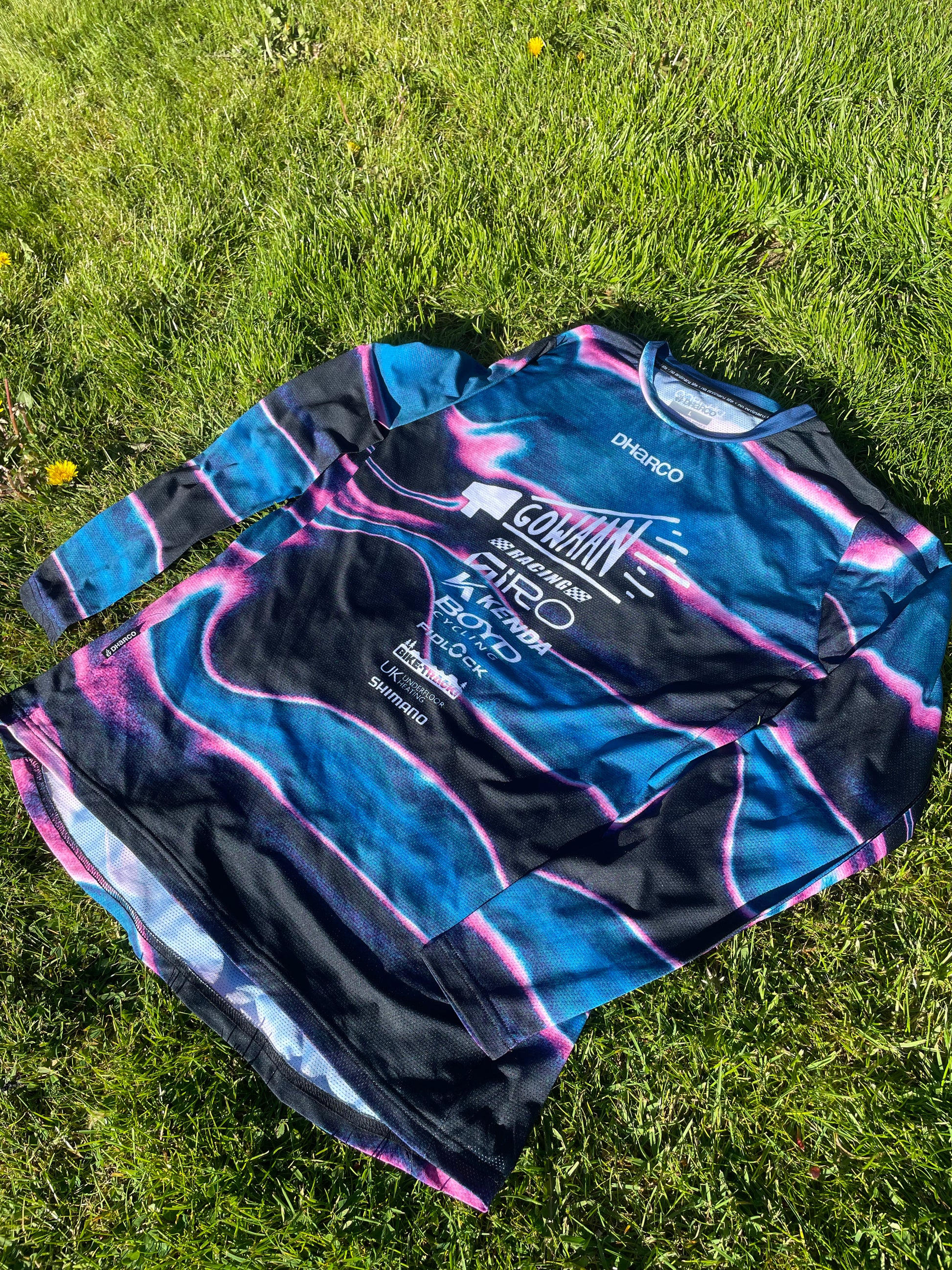 Blue and black Gowaan Racing long-sleeve Dharco jersey with brand logos on grass