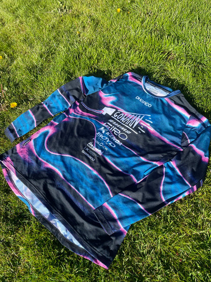 Blue and black Gowaan Racing long-sleeve Dharco jersey with brand logos on grass